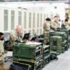 A group of military personnel in uniforms using computers and communication equipment in a secure indoor facility.