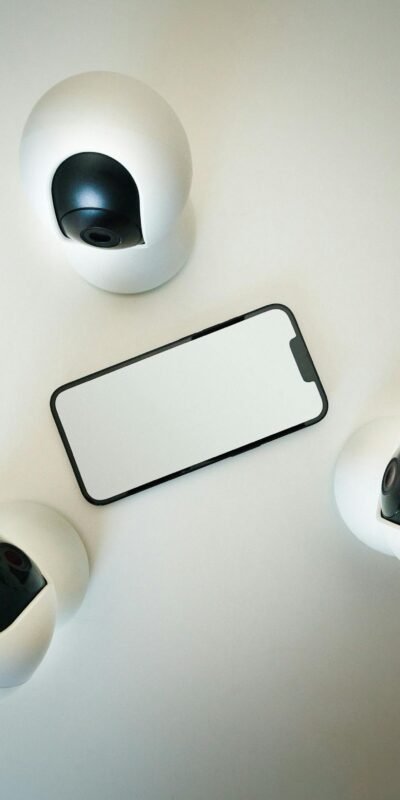 Smartphone surrounded by security cameras on a modern, minimalist setup.